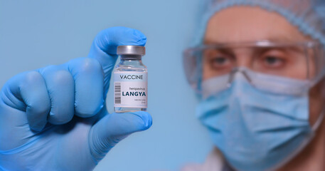 A doctor in safety glasses, medical hat, face mask and medical gloves holds an ampoule with Langya henipavirus (LayV) vaccine. Langya 2022 virus.The concept of medicine, healthcare, science.