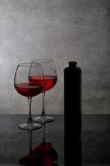 Still life with wine glasses and a bottle on a reflective surface