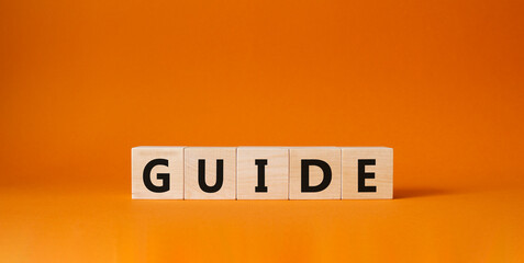 Guide symbol. Wooden cubes with word Guide. Beautiful orange background. Guide concept. Copy space.