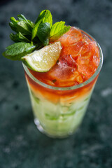 cocktail with lime and herbs on a marble table of a bar
