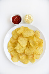 Fluted chips on a large plate with sauce and mayonnaise. Fast food fried potatoes with sauces.