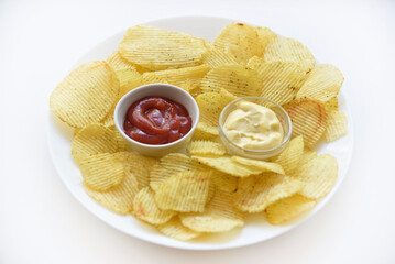 Fluted chips on a large plate with sauce and mayonnaise. Fast food fried potatoes with sauces.
