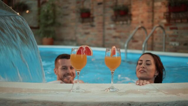 Young couple drinking cocktails in the swimming pool