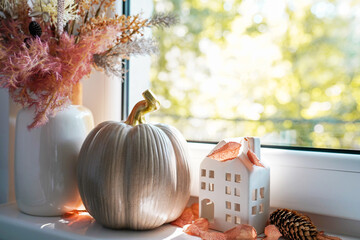 Autumn decor on a window, dried flowers, pumpkin and toy house, Sweet Home. Still life details in home on a wooden window
