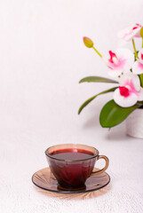 Obraz na płótnie Canvas Flower tea karkade. Delicious herbal tropical drink on a bright table. A cup of pink tea from dry hibiscus petals, a natural medicinal drink against the background of fern leaves. Tropical morning.