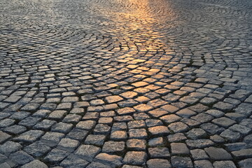 A street in the old town made of granite cubes illuminated by the setting sun - obrazy, fototapety, plakaty