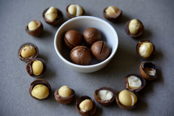 Delicious macadamia nut in a cup on a gray background. Broken nuts and shells.