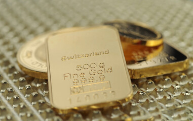 Gold bars and gold coins on a golden background. Selective focus.