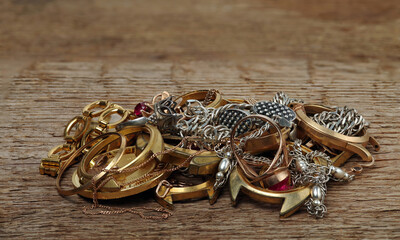 Old and broken gold and siver jewelry, watches of gold and gold-plated on a wooden background. A scrap of precious metals.