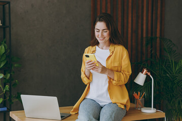 Young smiling happy fun successful employee business woman 20s she wear casual yellow shirt hold in...