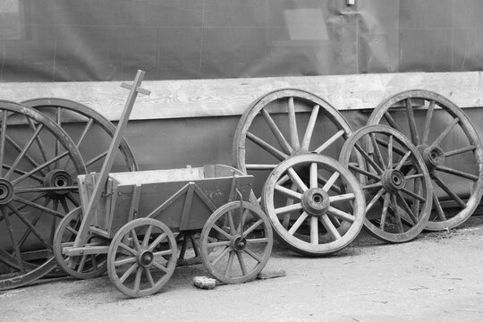 An old handcart and old wooden horse cart wheels leaning against the wall