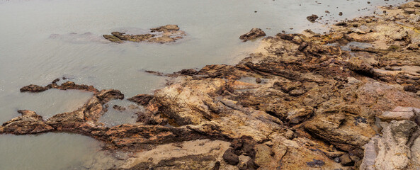 a brown rocky volcanic formations at beach