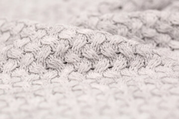 Knitted light surface of wool things as a background. Closeup of gray texture knitting patterns. Background with warm winter textile copy space.