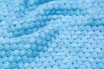 Knitted surface of woolen things as a background. Close-up of soft blue knitted patterns texture. Warm winter clothes. Background textile surface with copy space for text.