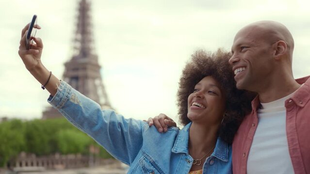 Happy multiethnic beautiful couple in love visiting Paris. Young man and woman on vacation in the french capital city, walking and doing activities around the eiffel tower area	