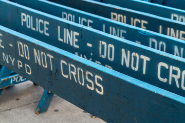 Close up view of several weathered and worn blue wooden road barricades with NYPD Police line do...