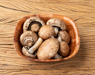 Portobello mushrooms in a bowl over wooden table