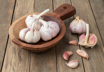 Garlic bulb and cloves on a plate over wooden table