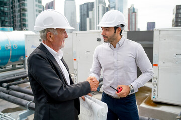 Close up shot senior engineer man shake hands for success project with young technician and they stay in construction site.