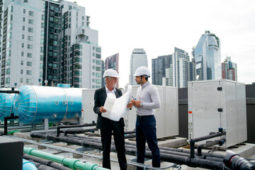 Wide shot of two engineers or technician man discuss together using building plan or drawing and...