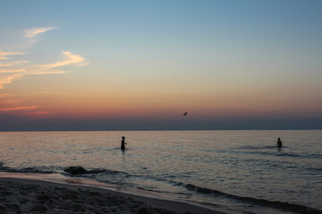 Beautiful sunset on the Polish beach in Międzywodzie. In the sea you can see two children playing. 10 August 2020