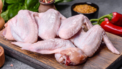 Raw chicken wings with ingredients for cooking on a wooden cutting board
