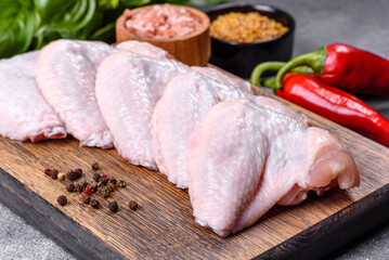 Raw chicken wings with ingredients for cooking on a wooden cutting board