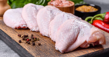 Raw chicken wings with ingredients for cooking on a wooden cutting board