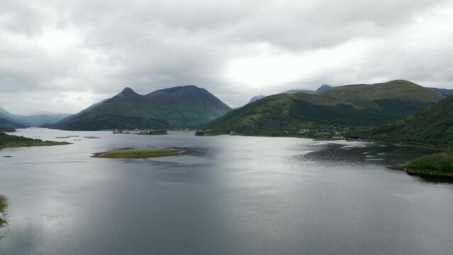 Aerial, rising up, Loch Leven and mountains in the Scottish Highlands, Marine Harvest salmon farm in background.