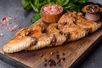 Baked chicken wings with sesame seeds and sauce on a wooden cutting board