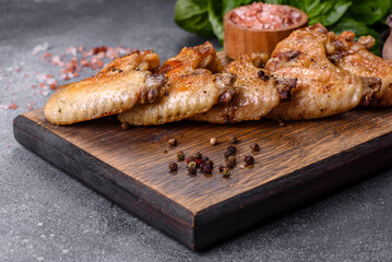 Baked chicken wings with sesame seeds and sauce on a wooden cutting board
