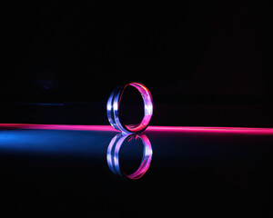 light rings, pink and blue, magenta and turquoise with reflections on the floor, black background, moving light rings