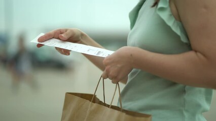 Woman looking at cash receipt after shopping. The girl looks at the increase in prices in the store