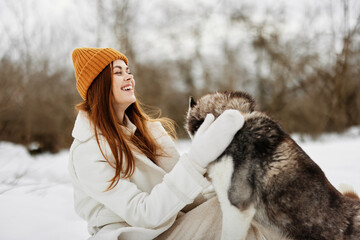 young woman in the snow playing with a dog fun friendship Lifestyle