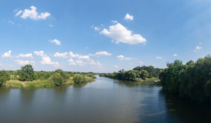 Fototapeta na wymiar Panorama rzeki Odry w tle lekko pochmurna pogoda, błękit nieba zieleń przy brzegu, pora letnia, Odra w odcinku województwa Opolskiego