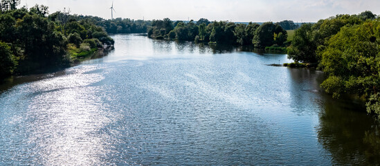 Panorama rzeki Odry w tle lekko pochmurna pogoda, błękit nieba zieleń przy brzegu,  pora letnia, Odra w odcinku województwa Opolskiego