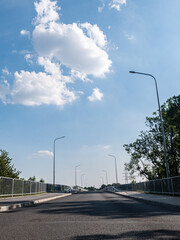 droga idąca przez most osłonięta barierkami i kratką w porze letniej, błękitne niebo, z prawie bezchmurną pogodą - obrazy, fototapety, plakaty