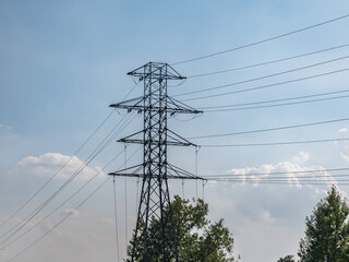 Fototapeta premium ścieżka elektryczna idąca drogą polną, błękit nieba lekko pochmurna pogoda w tle, pora letnia