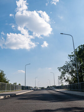 droga idąca przez most osłonięta barierkami i kratką w porze letniej, błękitne niebo, z prawie bezchmurną pogodą