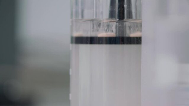 a tablet was thrown into a flask of water and dissolved by stirring water with a tablet. in the background flasks with leaves. close-up