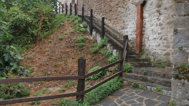 Des escaliers montants historiques et en pierre, de la nature et végétation, marches en angle, dans un village d'Espagne