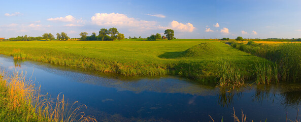 Beautiful summer landscape showing huge meadow on the river bank during sunny day
