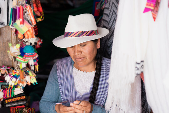 Retrato de una mujer indígena tejiendo usando un sombrero típico