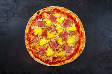 Traditionelle italienische Pizza Hawaii mit Schinken, Ananas und Mozzarella serviert als Draufsicht auf einem alten rustikalen Board mit Textfreiraum 