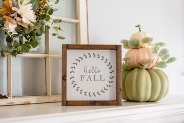Contemporary stacked pumpkins on the mantel with a sign that say