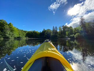 Kayak gonflable sur un lac paisible l'été. Pointe d'un canot jaune avec rame sur une rivière entourée de montagnes et d'une forêt. Pagayer sur l'eau calme. 