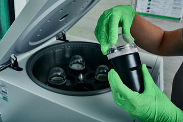 Laboratory scientist placing blood test tubes into centrifuge. Research medical laboratory
