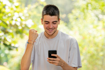 excited young man celebrating looking at mobile phone