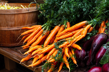 Selective focus view of bunch of carrots, displayed with eggplants and wax beans on each side next to them