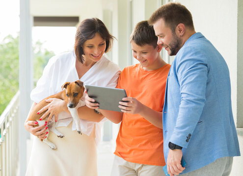 Portrait Of A Happy Joyful Family. Dad, Mom And Son Use A Tablet. With Cheerful Joyful Emotion.internet Shopping Online Banking Video Call Technology Concept